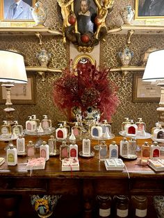 a table with many bottles on it in front of a portrait and two lamps next to each other