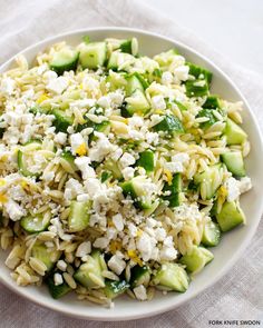 a white bowl filled with rice and cucumbers on top of a table cloth