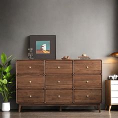 a wooden dresser sitting next to a potted plant on top of a hard wood floor