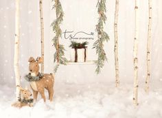 two deers are standing in the snow near some christmas decorations and trees with presents hanging from them