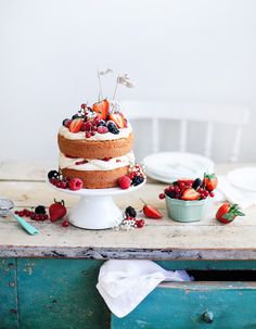 a cake with berries and whipped cream on top is sitting on a table next to other desserts