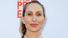 a woman with long hair wearing a white shirt and red lipstick on her lips is looking at the camera