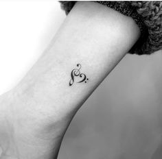 a black and white photo of a small tattoo on the ankle, with music notes