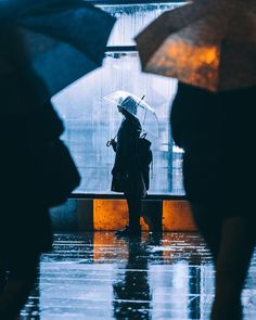 several people standing in the rain with umbrellas over their heads and one person holding an open umbrella