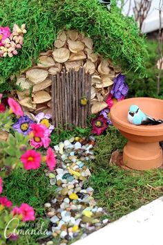 a fairy garden with a toilet and birdhouse in the middle, surrounded by flowers