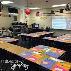 an empty classroom with desks and projector screen in the back ground, decorated with colorful papers