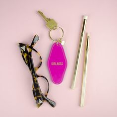 a pair of glasses, eyeglasses and keychain on a pink surface