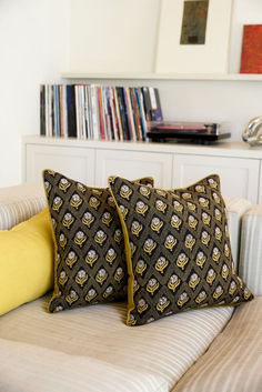 two pillows sitting on top of a couch in front of a book shelf filled with books