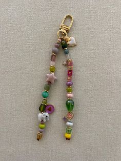 a key chain with beads and charms hanging from it's side on a white surface