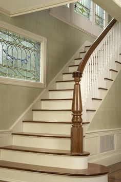 a staircase with stained glass windows and wooden handrails in a home's entryway