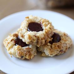 three cookies on a white plate with jelly in the middle and oatmeal filling