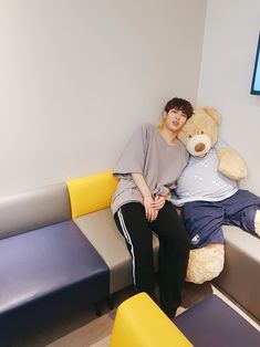 a person sitting on a couch with a teddy bear next to them in a waiting room