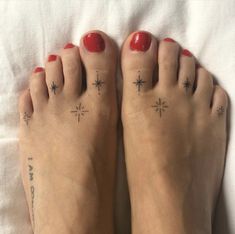 two feet with small tattoos on them and one has red nail polishes, while the other has black ink