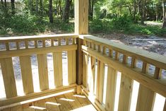 a wooden porch with railings and trees in the background