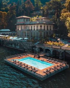 an empty swimming pool in front of a large building on the water's edge