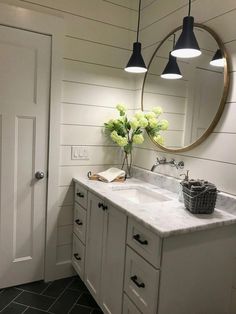 a bathroom with two sinks and a large round mirror