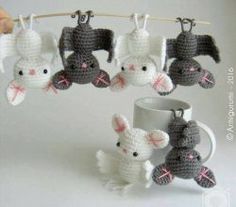 small crocheted animals hanging from a clothes line next to a coffee cup and mug