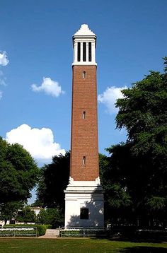 a tall brick tower with a clock on it's side in the middle of a park