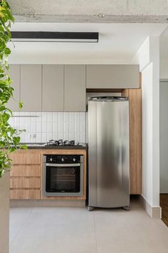 an empty kitchen with stainless steel appliances and wood cabinetry on the walls, along with white tile flooring