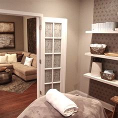 a living room filled with furniture next to a white door and shelves on the wall