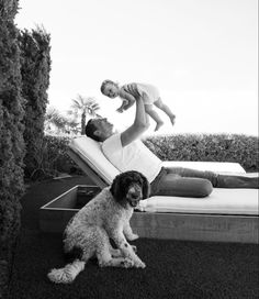 a man laying on top of a lawn chair next to a dog and a child