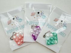 three bags of poppin'tins are sitting on the table with some key chains hanging from them