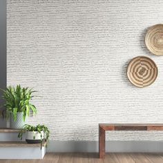 two baskets on the wall next to a wooden bench and potted houseplant