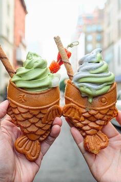 two people holding ice cream cones with green and blue icing on them in their hands