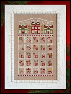 a cross stitch christmas calendar hanging on a wall next to a red and white frame