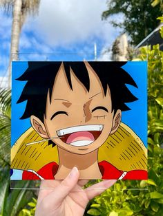 a hand holding up a card with an image of gohan from one piece of anime