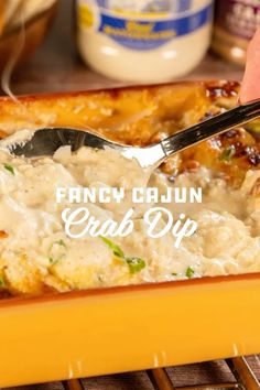 a person holding a spoon in a casserole dish with the words fancy cajun crab dip on it