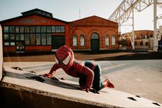 a person in a spiderman suit is on a skateboard and has his head down