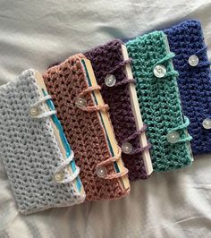 four crocheted notebooks lined up on a bed