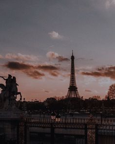 the eiffel tower towering over paris at sunset with clouds in the sky behind it