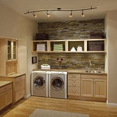 a washer and dryer in a room with wood floors, cabinets and shelves