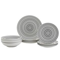 four white bowls and two plates with circular designs on the sides, all in different sizes