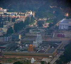 an aerial view of a city with lots of buildings in the foreground and trees on the other side