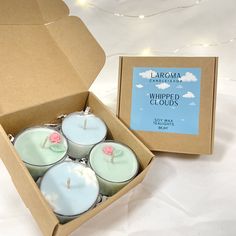 six candles in a cardboard box on a white surface