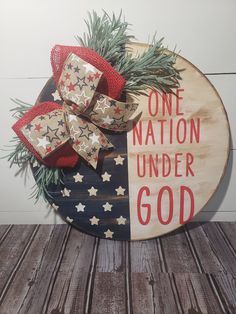 a wooden sign that says, one nation under god with bows and evergreen branches on it