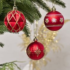 three red ornaments hanging from a christmas tree