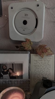 a white alarm clock sitting on top of a wall next to pictures and a candle