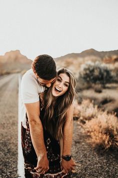 a man and woman hugging on the side of a road in the middle of nowhere