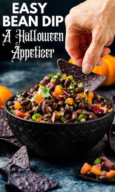 a hand dipping a tortilla chip into a bowl filled with black beans and vegetables