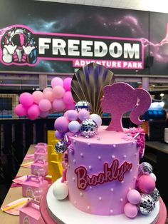 a pink and purple birthday cake on display at a party for children's birthday