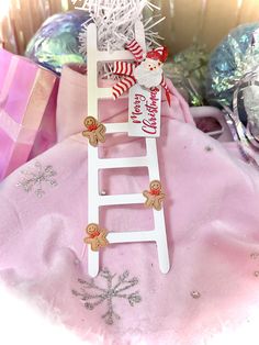 a wooden ladder decorated with christmas decorations and candy canes is sitting on a pink blanket