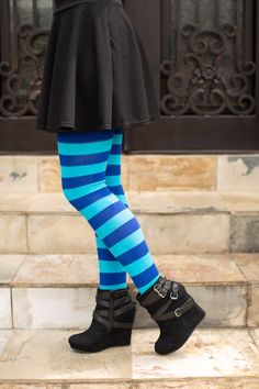 a woman in blue and black striped tights standing on steps with her legs crossed