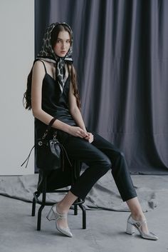 a woman sitting on a chair with a scarf around her head and wearing high heels