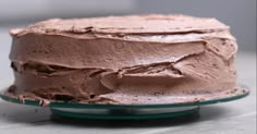 a chocolate cake sitting on top of a glass plate covered in frosted icing