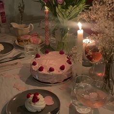 a table topped with a cake covered in frosting and strawberries next to candles