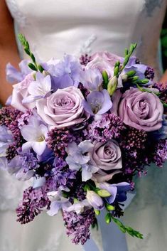 a bride holding a bouquet of purple flowers